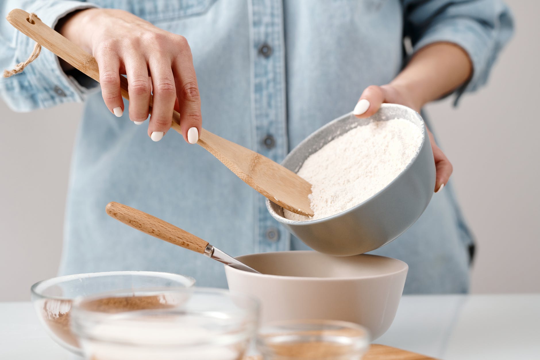 person adding flour into a bowl